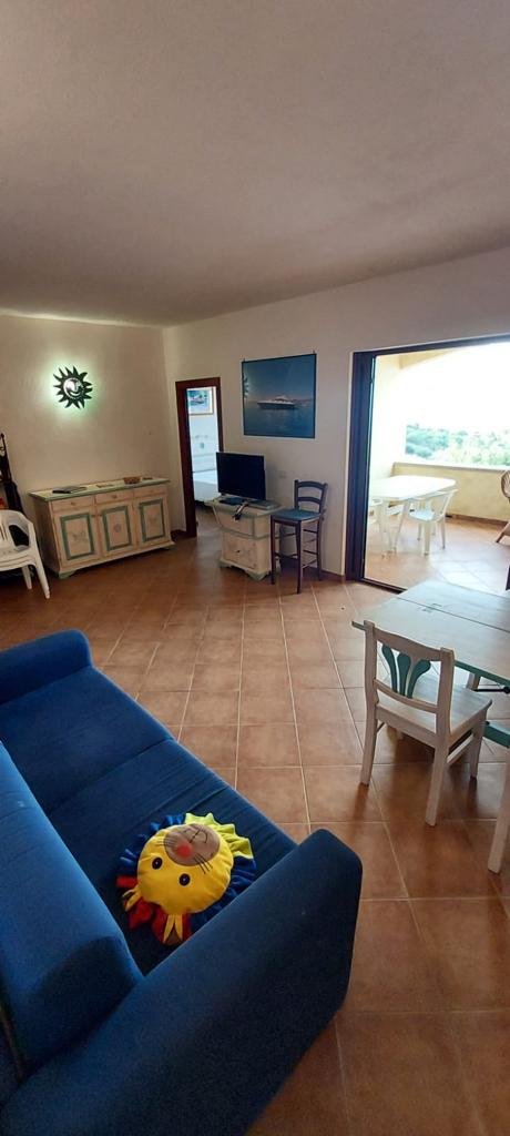 Soggiorno del Corbezzolo con divano blu, tavolo e sedie