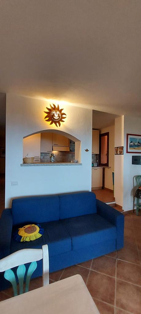 Salotto del Corbezzolo con divano blu e decorazione a sole